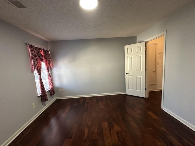 unfurnished room featuring dark hardwood / wood-style flooring and a textured ceiling