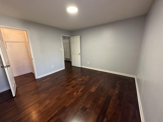 unfurnished bedroom with dark hardwood / wood-style floors, a walk in closet, and a closet