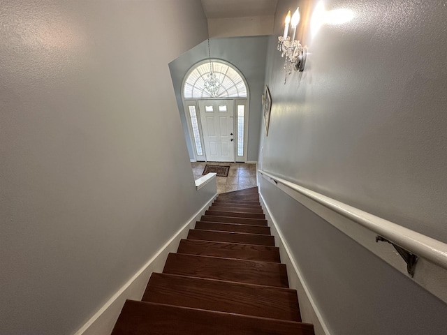 stairway with tile patterned floors and a chandelier