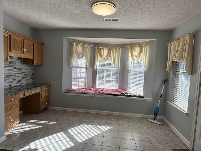 unfurnished dining area with light tile patterned flooring and a textured ceiling