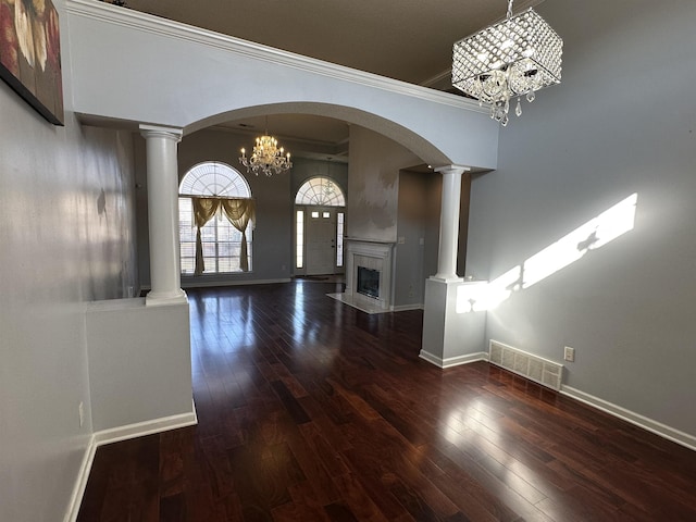 interior space with dark hardwood / wood-style floors, crown molding, a fireplace, and a chandelier