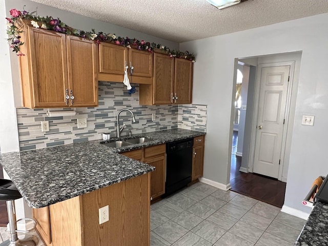 kitchen featuring sink, a textured ceiling, black dishwasher, a kitchen bar, and kitchen peninsula