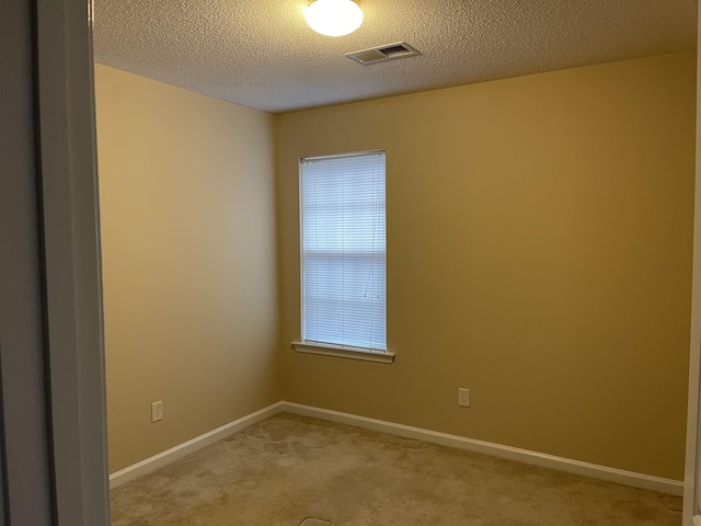 carpeted empty room featuring a textured ceiling