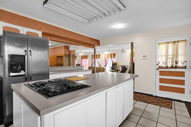 kitchen with stainless steel refrigerator with ice dispenser, light tile patterned floors, black gas cooktop, a center island, and white cabinetry