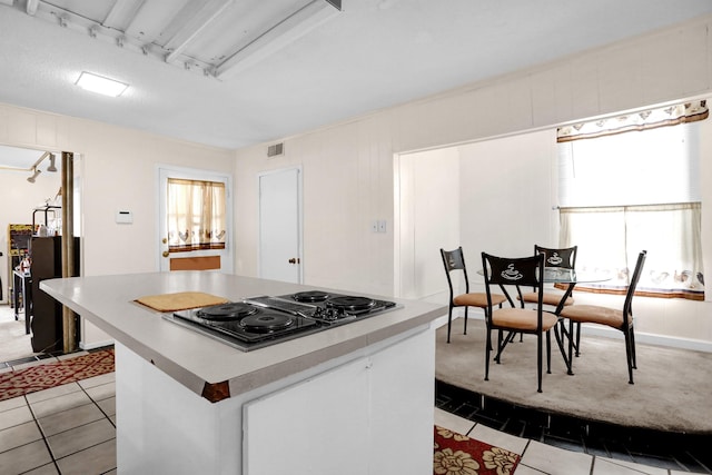 kitchen with white cabinets, a center island, light tile patterned floors, and gas cooktop