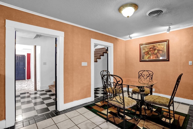 tiled dining area with ornamental molding and a textured ceiling