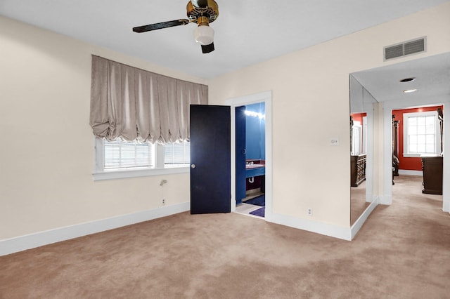 unfurnished bedroom with ensuite bath, ceiling fan, and light colored carpet