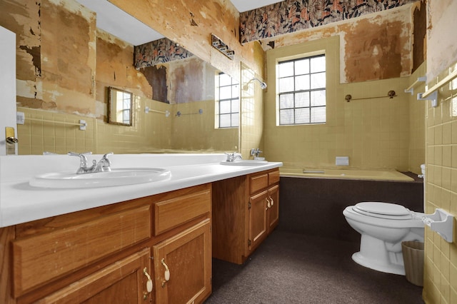 bathroom with a washtub, toilet, and vanity