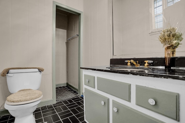 bathroom featuring vanity, toilet, and wood walls