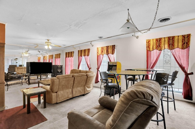 living room featuring light carpet, a textured ceiling, plenty of natural light, and ceiling fan