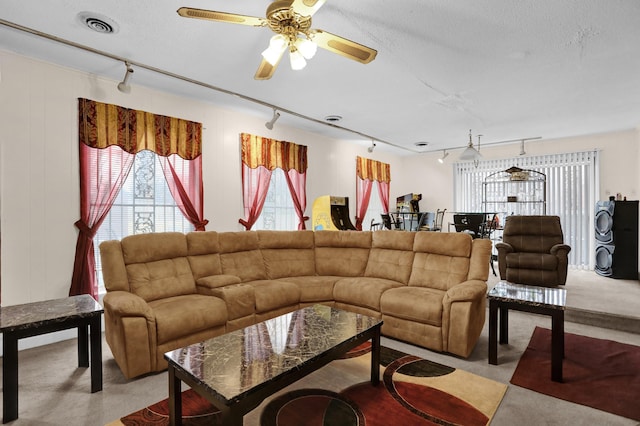 carpeted living room featuring ceiling fan, track lighting, and a textured ceiling