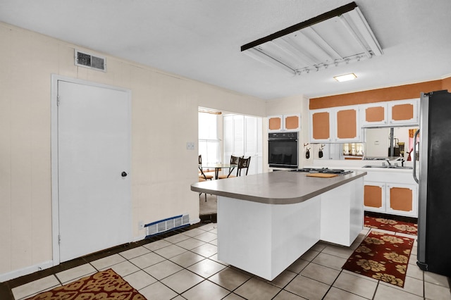 kitchen featuring white cabinets, sink, light tile patterned flooring, a kitchen bar, and stainless steel appliances