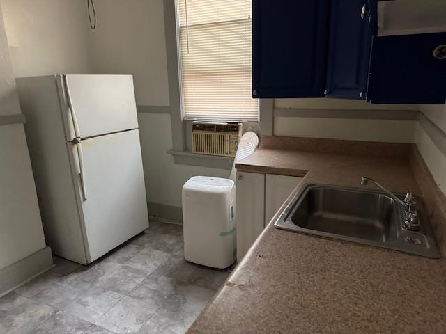 kitchen with cooling unit, sink, blue cabinets, and white refrigerator