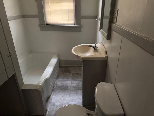 bathroom with a washtub, vanity, and toilet