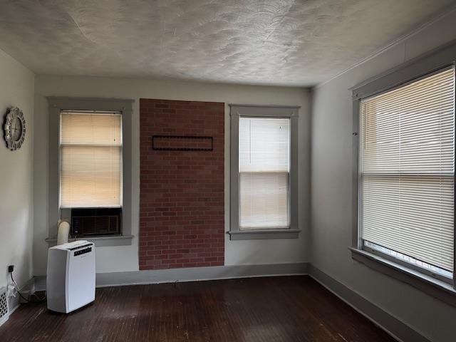 spare room featuring cooling unit, plenty of natural light, and dark wood-type flooring