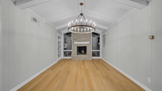 unfurnished living room with a fireplace, hardwood / wood-style floors, lofted ceiling with beams, and a notable chandelier