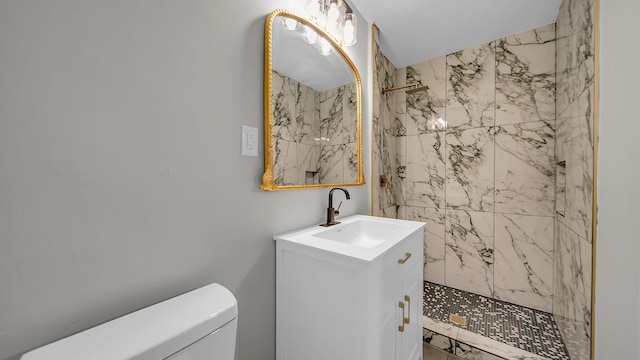 bathroom featuring a tile shower, vanity, and toilet