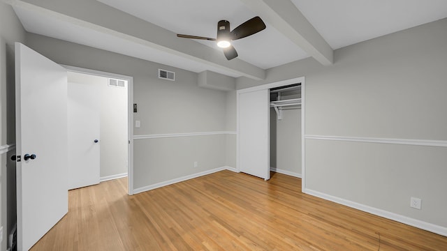 unfurnished bedroom featuring beamed ceiling, ceiling fan, a closet, and light hardwood / wood-style flooring