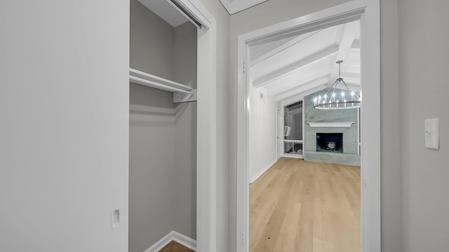 hallway featuring lofted ceiling with beams, hardwood / wood-style flooring, and an inviting chandelier