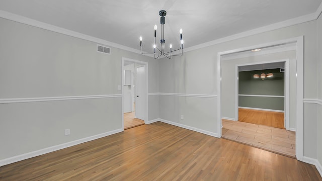 unfurnished dining area featuring hardwood / wood-style floors, crown molding, and an inviting chandelier