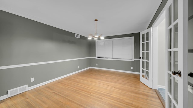 unfurnished dining area featuring a notable chandelier, light wood-type flooring, and french doors