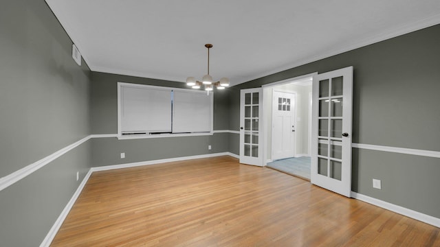 unfurnished dining area featuring hardwood / wood-style flooring, a notable chandelier, crown molding, and french doors