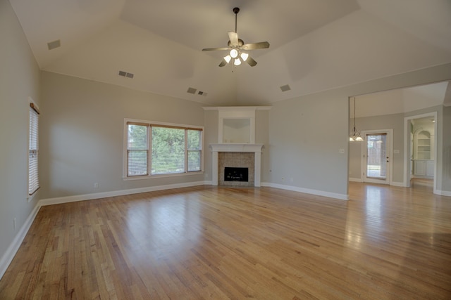 unfurnished living room with ceiling fan, high vaulted ceiling, a tiled fireplace, and light hardwood / wood-style floors