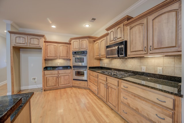 kitchen with light hardwood / wood-style flooring, ornamental molding, stainless steel appliances, and dark stone counters