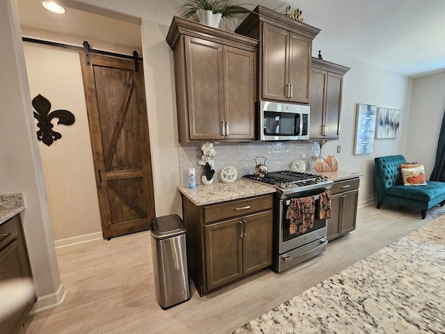 kitchen with a barn door, stainless steel appliances, and dark brown cabinetry