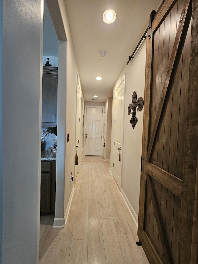 hallway featuring a barn door and light hardwood / wood-style floors