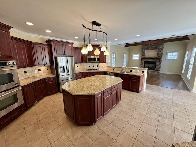 kitchen with kitchen peninsula, pendant lighting, a fireplace, light tile patterned floors, and appliances with stainless steel finishes