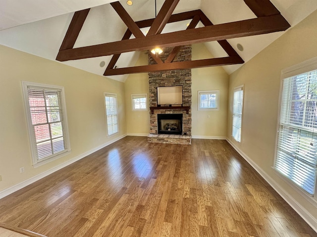 unfurnished living room featuring beam ceiling, wood-type flooring, a fireplace, and high vaulted ceiling