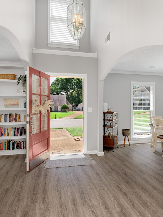 foyer with wood-type flooring, a towering ceiling, and an inviting chandelier