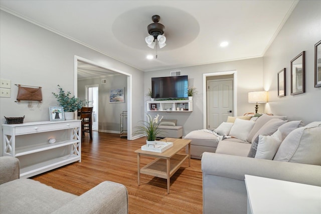 living room featuring light wood-type flooring, ceiling fan, and ornamental molding