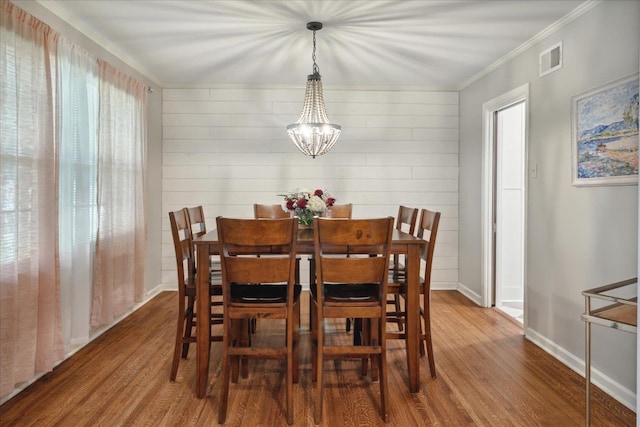 dining space featuring an inviting chandelier, ornamental molding, and hardwood / wood-style flooring