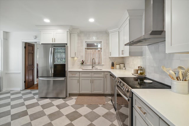 kitchen featuring sink, wall chimney exhaust hood, tasteful backsplash, white cabinetry, and stainless steel appliances