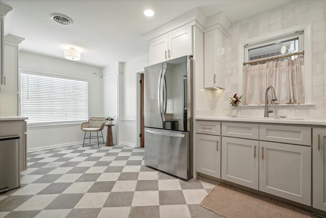 kitchen featuring white cabinetry, sink, and stainless steel refrigerator