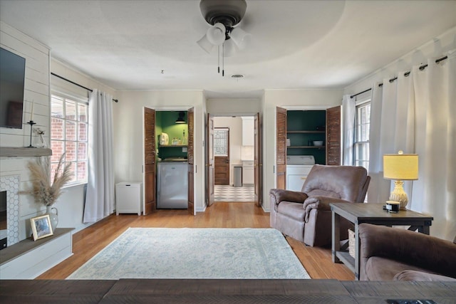 living room featuring washer / clothes dryer, light hardwood / wood-style flooring, and ceiling fan