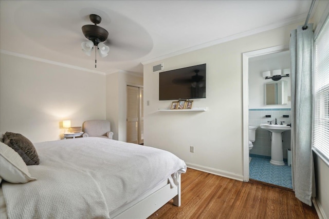 bedroom with ornamental molding, ceiling fan, hardwood / wood-style flooring, connected bathroom, and a closet