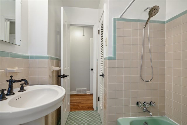 bathroom featuring sink, tile walls, and tiled shower / bath