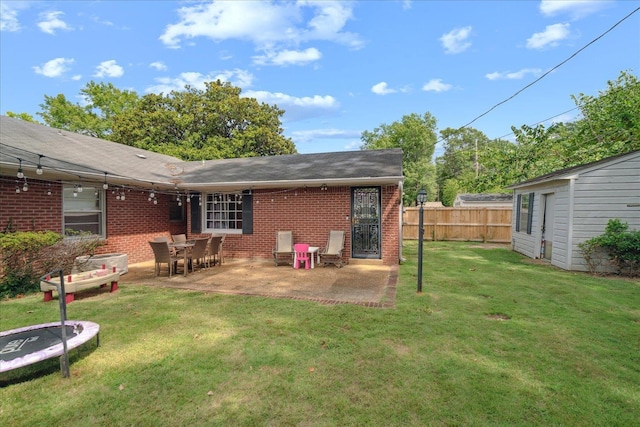 rear view of property featuring a trampoline, a patio area, and a lawn