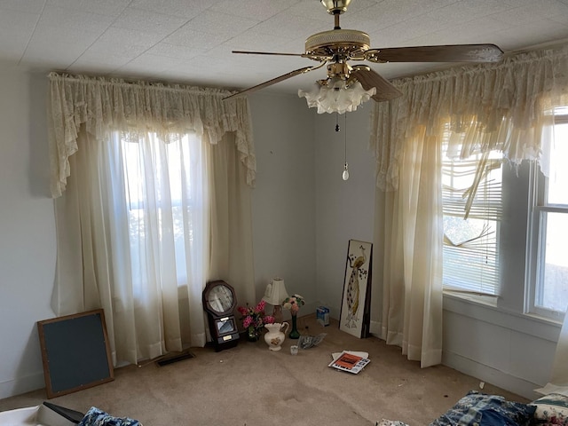 interior space featuring light carpet, ceiling fan, and a healthy amount of sunlight