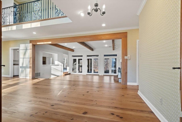 unfurnished living room featuring beam ceiling, hardwood / wood-style flooring, an inviting chandelier, and ornamental molding