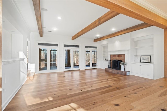 unfurnished living room featuring built in features, a fireplace, a wealth of natural light, and french doors