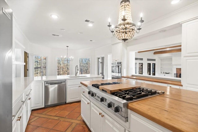 kitchen featuring white cabinets, sink, appliances with stainless steel finishes, and an inviting chandelier