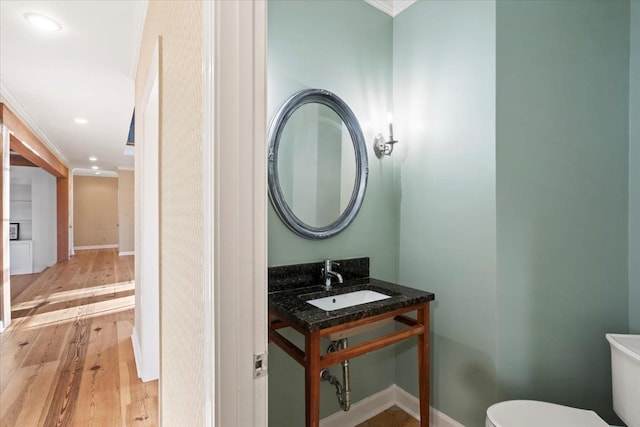 bathroom featuring hardwood / wood-style flooring, toilet, ornamental molding, and sink