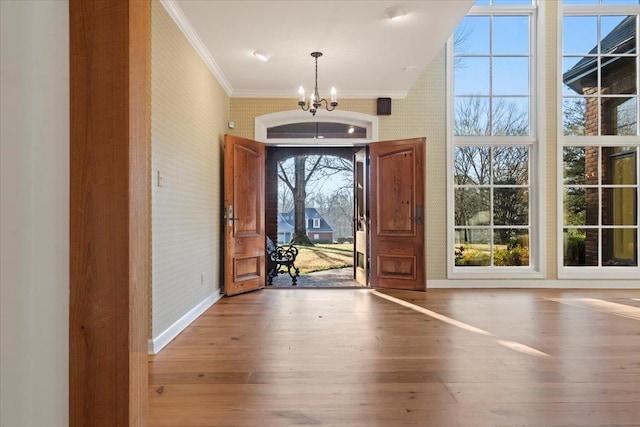 foyer featuring wood-type flooring, an inviting chandelier, and ornamental molding