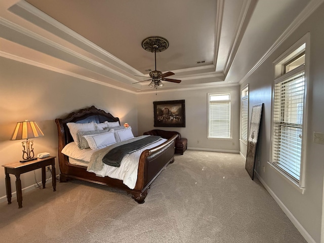 carpeted bedroom with a tray ceiling, ceiling fan, and crown molding