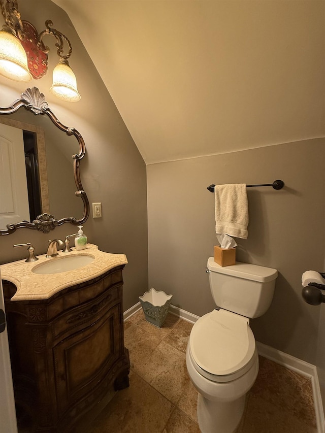 bathroom featuring vanity, toilet, and lofted ceiling