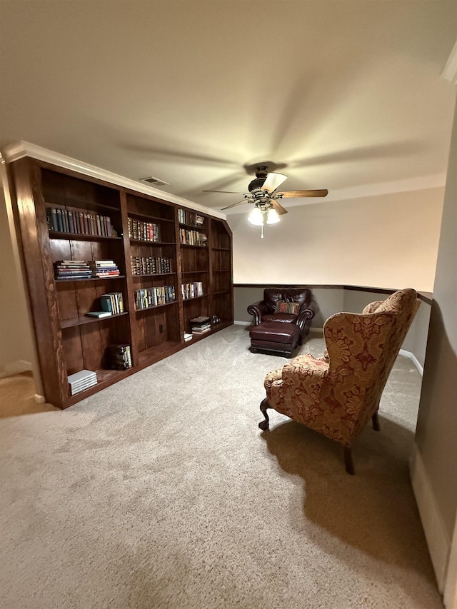 sitting room with carpet flooring, ceiling fan, and crown molding